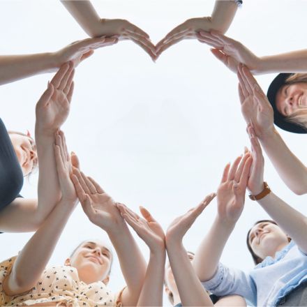people in a circle making a heart with their hands