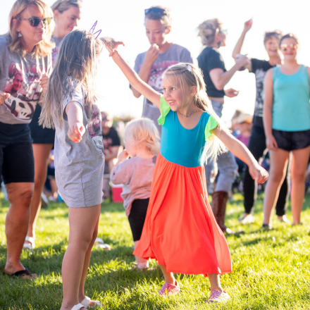 young girls playing in field with people behind them