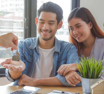 mortgage lender handing keys to a young couple