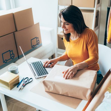 woman with packing boxes looking at laptop