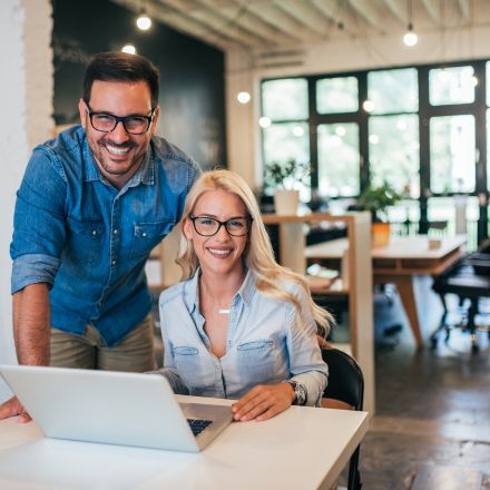 man and woman smiling and looking at laptop